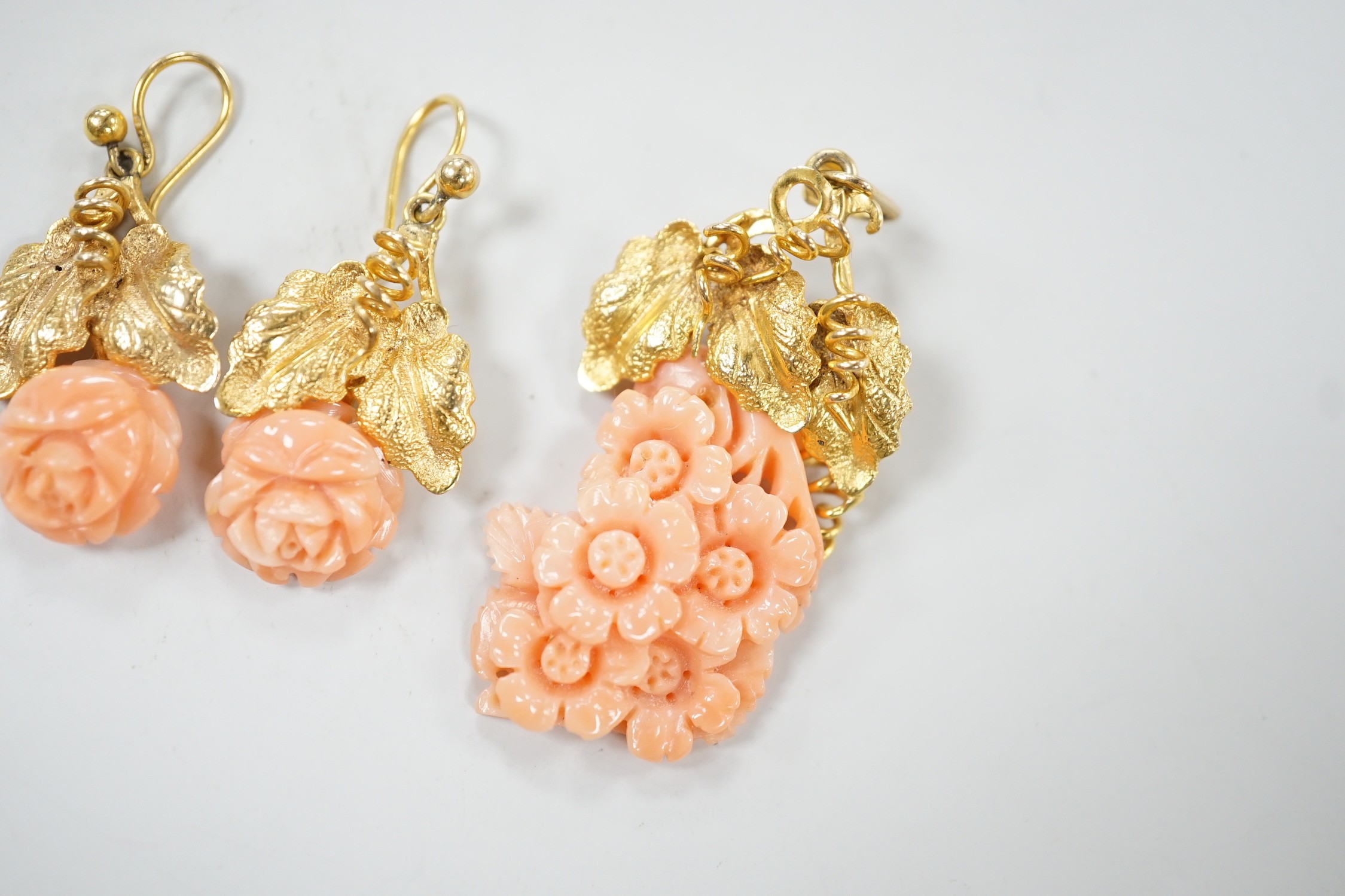 A modern suite of yellow metal and carved coral jewellery, comprising a pendant , 40mm, on chain, 45cm and a pair of matching drop earrings stamped 9ct gold, 26mm, gross 15.2 grams.